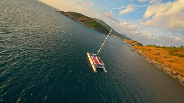 Fpv drone flight around a nice yacht at a creek at Phuket island, Thailand. Aerial dynamic fast flight during beautiful sunset with small sea waves ripples