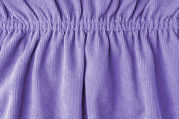 Purple corduroy fabric gathered with elastic close-up. Velveteen texture with folds and drapery....