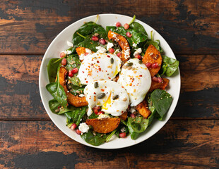 Roasted butternut squash salad served with poached eggs, spinach, nuts and pomegranate seeds