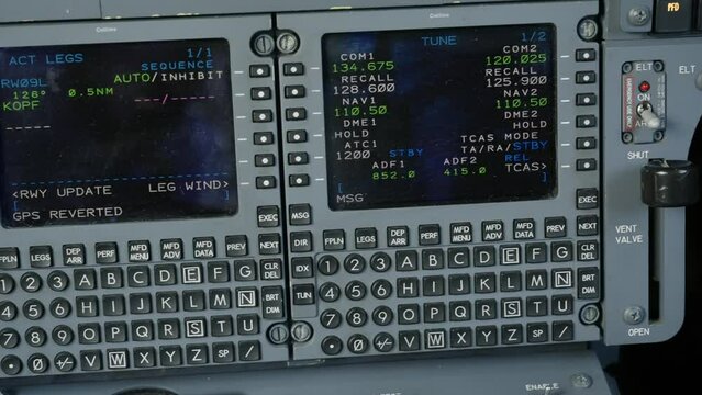 Trucking shot of pilot's control display units inside jet cockpit. Interface devices accessing Hawker's flight management computers