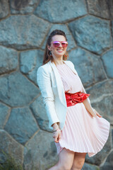 smiling trendy 40 years old woman in dress and jacket in city