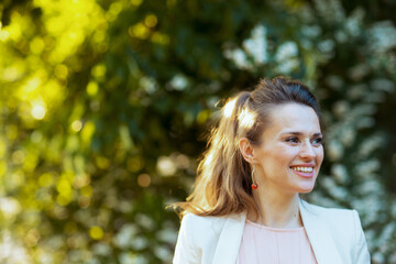 happy modern female in pink dress and white jacket in city