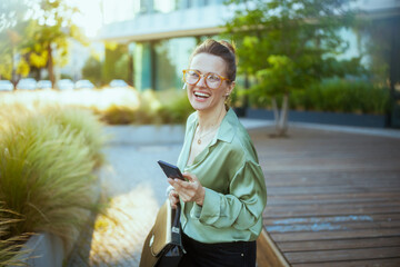 woman worker in green blouse using phone and walking