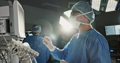 Team, surgeon and press monitor in hospital, clinic and operation theater. ECG, doctor and medical professional on tech for heart rate monitor, cardiology and man on electrocardiogram on lens flare - Powered by Adobe