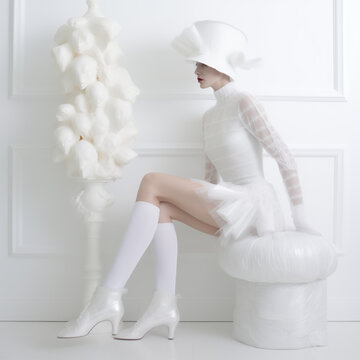 Photo de mode d'une femme habill&eacute;e avec une robe blanche et des bas blancs, d&eacute;cor &eacute;pur&eacute;, voile et nacre,