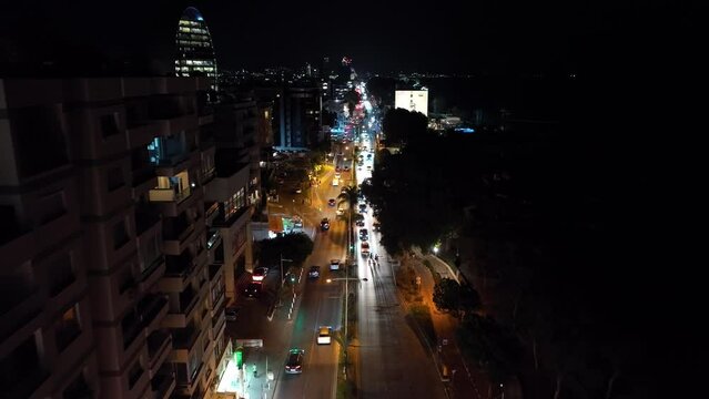 Aerial view of the cityscape of Limassol at night. Street lights and car headlights on the road in a windy season in a resort town. High quality 4k footage