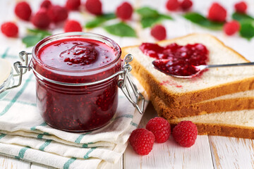 Delicious toast with raspberry jam on the wooden kitchen table.