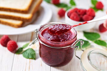 Plate with toast and sweet raspberry jam on light wooden table. Toast with tasty raspberry jam on a white wooden table.