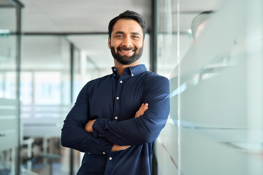 Happy Indian businessman professional leader standing arms crossed in office. Smiling male employee, business man company executive manager, confident eastern entrepreneur at work, portrait.
