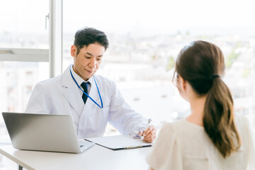 Fototapeta premium 診察・診療・問診・カウンセリングをする医者・医師・ドクターの男性と女性 