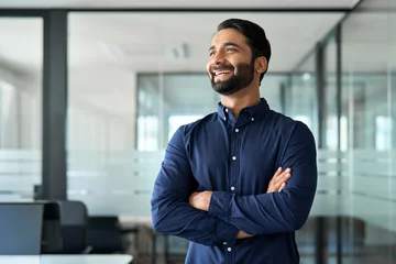 Fotobehang Happy confident Indian business man leader looking away standing in office. Smiling professional businessman manager executive, male worker from India feeling cheerful thinking of financial success. © insta_photos