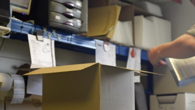 Close-up of a small internet business owner preparing  orders for customers, adding an address reading for posting