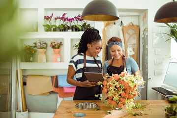 Florists collaborate over digital designs in a flower shop