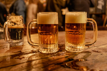 Mugs with pilsner beer in a wood table in a pub.