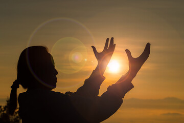 Silhouette woman on sunset background. Woman raising his hands in worship. Christian Religion...