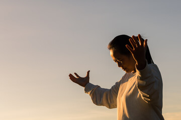 Silhouette woman on sunset background. Woman raising his hands in worship. Christian Religion...