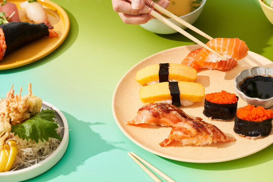 Sushi Wonderland cool tones and hand picking up nigiri with chopsticks 