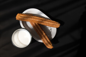Glass of milk and flour churros with sugar and cinnamon with space for text right dark background