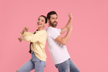 Happy couple dancing together on pink background