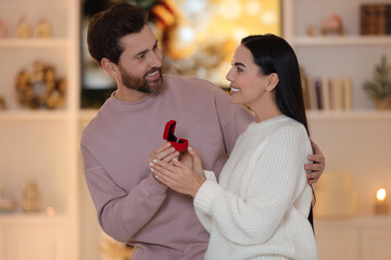 Making proposal. Man with engagement ring surprising his girlfriend at home on Christmas