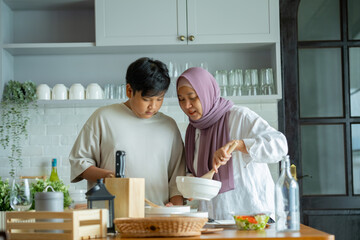 Cute son And His Muslim Mom In Hijab Preparing Pastry For Cookies In Kitchen, Baking Together At Home. Islamic Lady With son Enjoying Doing Homemade Pastry, preparing to cook breakfast for her family.