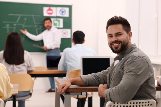 Happy man at desk in class during lesson in driving school