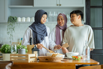 Cute Girl and Son and Her Muslim Mom In Hijab Preparing Pastry For Cookies In Kitchen, Baking Together At Home. Islamic Lady With Daughter and son Enjoying Doing Homemade Pastry