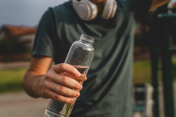 man young male teenager hold bottle of water drink training outdoor