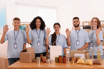 Portrait of volunteers and food products at table in warehouse