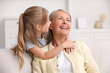 Happy grandmother hugging her granddaughter at home