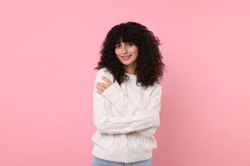 Happy young woman in stylish white sweater on pink background