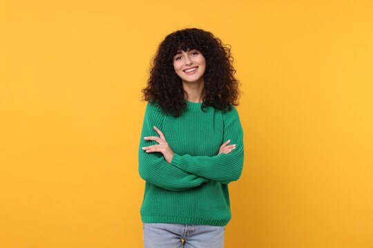 Happy young woman in stylish green sweater on yellow background