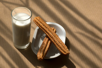 Glass of milk and flour churros with sugar and cinnamon in Mexico