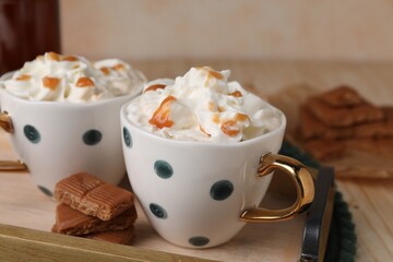 Delicious coffee with whipped cream and caramel syrup on wooden table, closeup