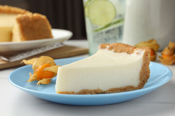Piece of tasty vegan tofu cheesecake and physalis fruit on white table, closeup