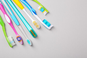 Many different toothbrushes on light background, flat lay. Space for text