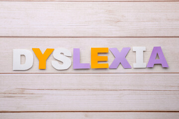 Word Dyslexia made of paper letters on wooden table, flat lay