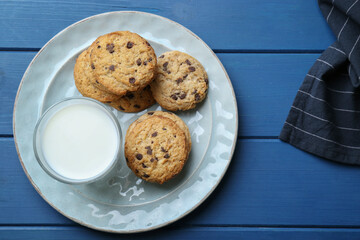 Tasty chocolate chip cookies and glass of milk on blue wooden table, flat lay