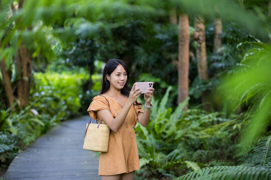 Tourist woman use cellphone to take photo in forest park