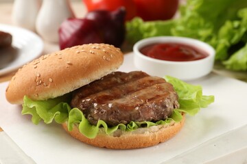 Delicious fried patty, lettuce and buns on white table, closeup. Making hamburger