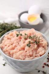 Fototapeta na wymiar Fresh raw minced meat and thyme in bowl on white wooden table, closeup