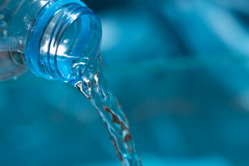 water flowing from a bottle. water pouring into the glass. Pouring water from bottle into glass on blue background.