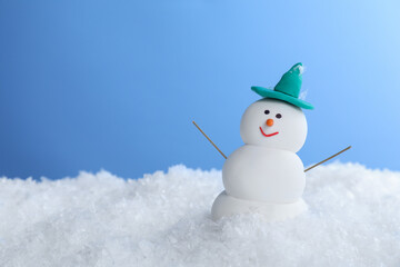 Funny snowman on snow against light blue background, space for text