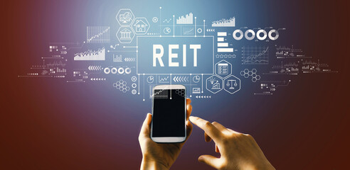 REIT - Real Estate Investment Trust theme with hand pressing a button on a technology screen