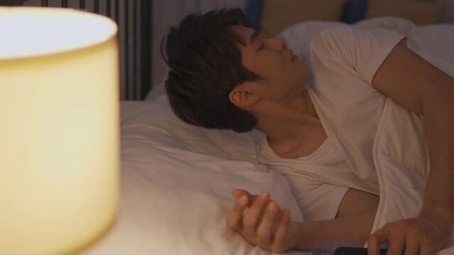 Asian man secretly chatting to mistress while lying in bed with girlfriend. 