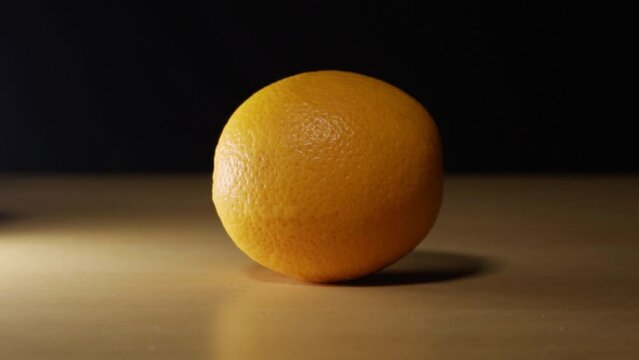Fresh orange laying on a table with black screen background.