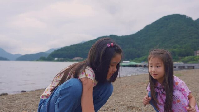 Asian adorable sibling girl playing sand around Mount Fuji in bright day. 