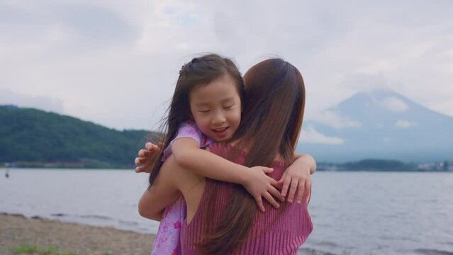 Asian mother and daughter hugging each other in mountain Fuji view. 