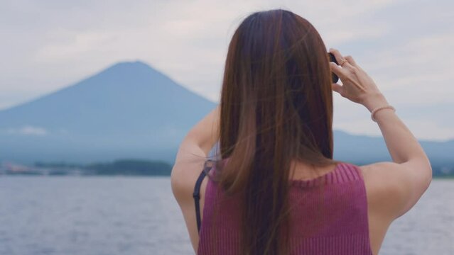 Asian beautiful woman use mobile phone taking a picture of mount Fuji. 
