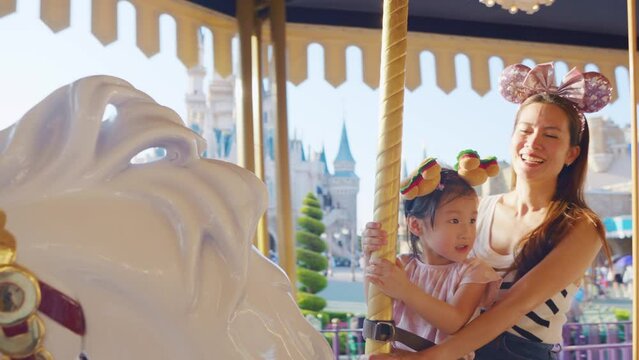 Asian mother and young daughter traveling in the theme park together. 